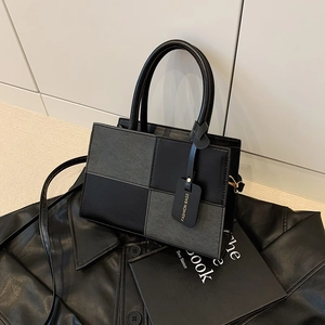 Minimalist color-block satchel bag with stylish top handles and a hanging fashion tag