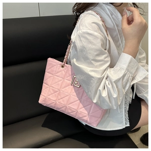 Detailed close-up of pink quilted crossbody bag with metal chain strap and logo