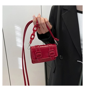 Detail of red patent leather mini bag with decorative chunky chain and crossbody strap