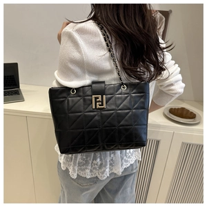 Detail of black quilted tote bag with gold geometric buckle and chain strap