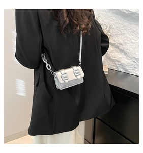 Detail view of mini silver laser crossbody bag with dual buckles and plastic chain link