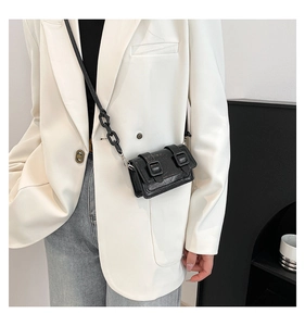 Detail of black mini crossbody bag with glossy crackle texture and chain strap