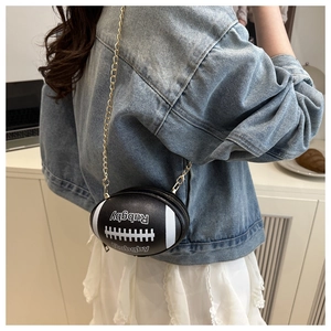 Detailed view of rugby ball shaped crossbody bag with gold chain strap on a model