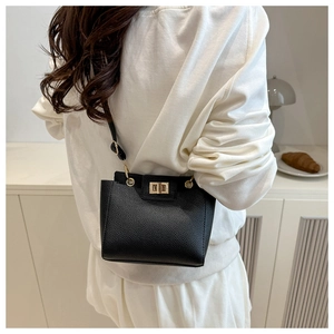 Détail du sac à bandoulière noir en cuir grainé avec un fermoir doré tournant élégant