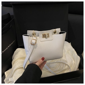 Détails de la texture du cuir litchi blanc avec fermoir pivotant doré sur un sac chic