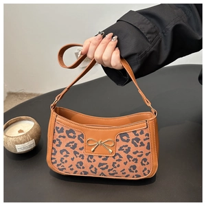Detail of leopard print handbag with golden bow decoration and brown leather strap
