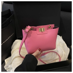 Détail macro du sac rose en cuir avec fermoir doré dans un coffret cadeau élégant