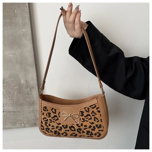 Detail of leopard print hobo bag featuring a golden metal bow and brown leather trim
