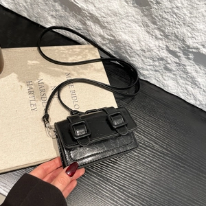 Mini black crossbody bag with glossy cracked texture and sleek rectangular flap design