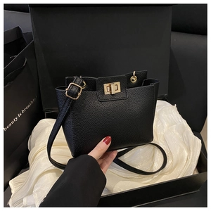 Détail du sac en cuir grainé noir avec fermoir rotatif doré dans un coffret cadeau