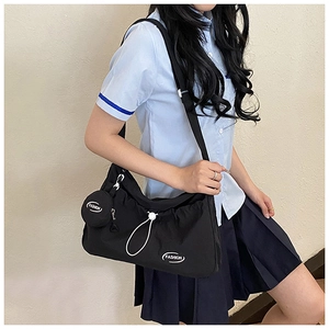 Detail der schwarzen Messenger-Tasche mit weißem Kordelzug und modischem Münzbeutel-Anhänger