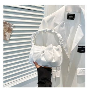 Detail of white ruched handbag with a large silk bow and chic silver chain strap