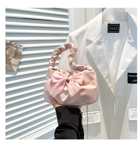 Close-up of pink pleated handbag with large organza bow detail and stylish chain strap