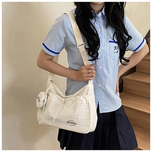 Detail of off-white canvas tote bag featuring pleated front pocket and a small coin purse