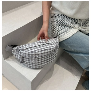 Close-up of gray checkered crossbody bag with multi-layer zippers and woven strap