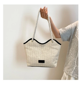 Detail of woven straw tote bag with rope handle and stylish black leather trim