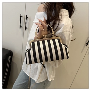 Detail view of striped tote bag with vintage metal frame clasp and engraved round handle