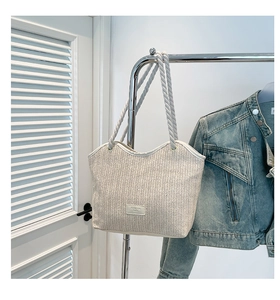 Close-up of beige woven tote bag with chunky rope handles and herringbone texture