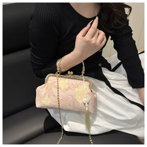 Detail of vintage floral handbag with gold metal handle, chain strap, and green tassel