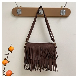 Close-up of bohemian dark brown suede bag featuring tiered tassels and adjustable strap