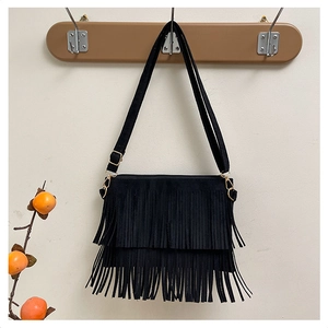 Close-up of black fringe shoulder bag with matte texture and gold-tone metal hardware