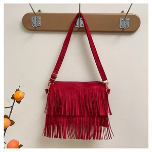 Detail of red suede crossbody bag featuring tiered fringe tassels and gold metal buckles