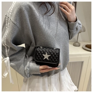 Détail d'un sac bandoulière noir matelassé avec étoile en strass argentée et chaîne en métal