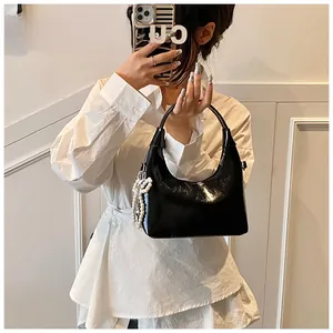 Glossy black hobo bag with pearl charm shown in a mirror selfie for size reference