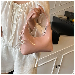 Detail of pink patent leather crescent bag with pearl bow pendant and zipper closure