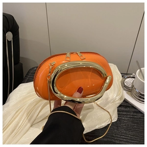 Detail of orange patent leather pillow bag with gold ring handle and snake chain strap