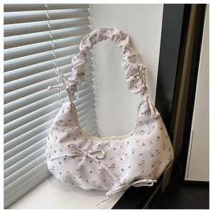 Detail of floral crescent shoulder bag featuring pleated handle and bow decoration