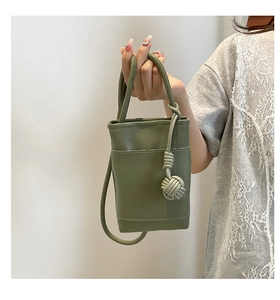 Detail view of mini olive green bucket bag with lychee texture and knot charm