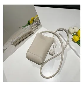 Detail shot of cream leather mini crossbody bag with braided knot strap on a mirror