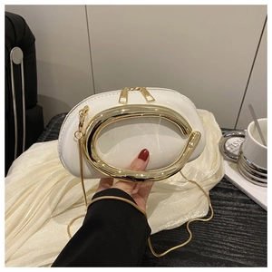 Detail of white glossy leather handbag featuring a large gold metal circular handle