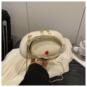 Detail of cream pillow bag featuring gold oval handle and sleek metallic chain strap