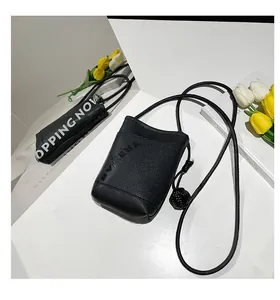 Detail of black mini crossbody bag featuring litchi texture and BV KENA embossed logo