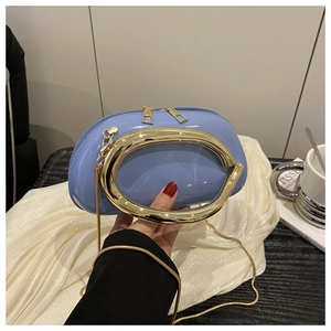 Close-up of light blue glossy pillow bag with large gold metal handle and chain strap