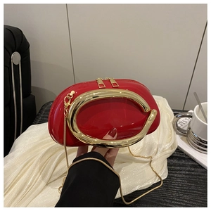 Close-up of red glossy pillow bag with large gold circular handle and fine metal chain