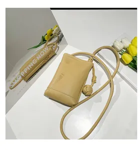 Detail of light yellow lychee grain leather mini bag with decorative hand-woven ball knots