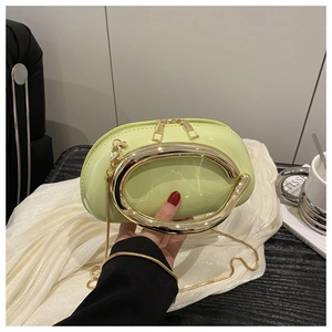 Detail of mint green patent leather bag with oversized oval gold handle and chain