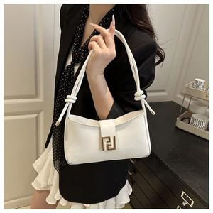 Detail of white baguette bag featuring a large gold metal F-shaped clasp and knot handle