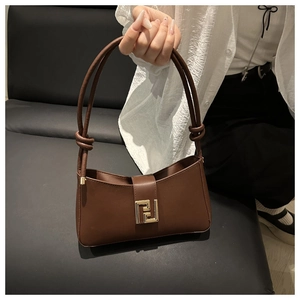 Detailed shot of brown baguette bag featuring a gold buckle and knotted strap detail