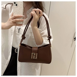 Mirror selfie showing a brown leather shoulder bag with knotted strap and gold buckle