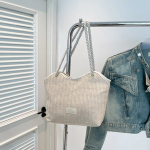 Retro woven straw tote bag with rope handles and fashion tag on white background