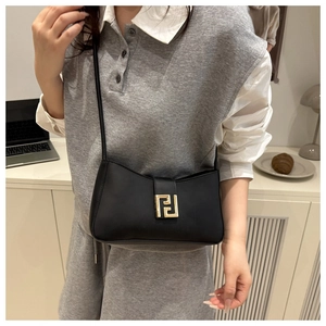 Detail of black leather crescent underarm bag featuring a golden metal buckle and thin strap