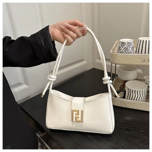 Detail of white leather shoulder bag featuring a decorative gold geometric buckle