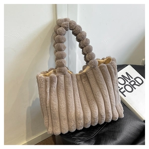Detail of taupe plush tote bag featuring vertical ribbed texture and fuzzy ball handle