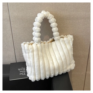 Detail of plush tote bag showing creamy faux fur texture and unique pom-pom ball handle