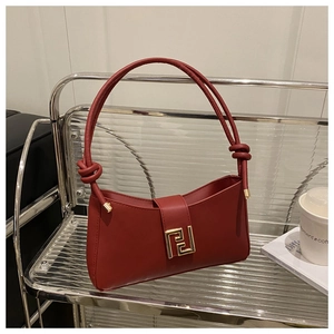 Detail of dark red leather underarm bag featuring a golden metal buckle and knot handle
