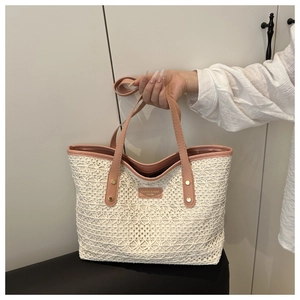 Detail of hollow-out woven texture and pink leather handle on a stylish white tote bag